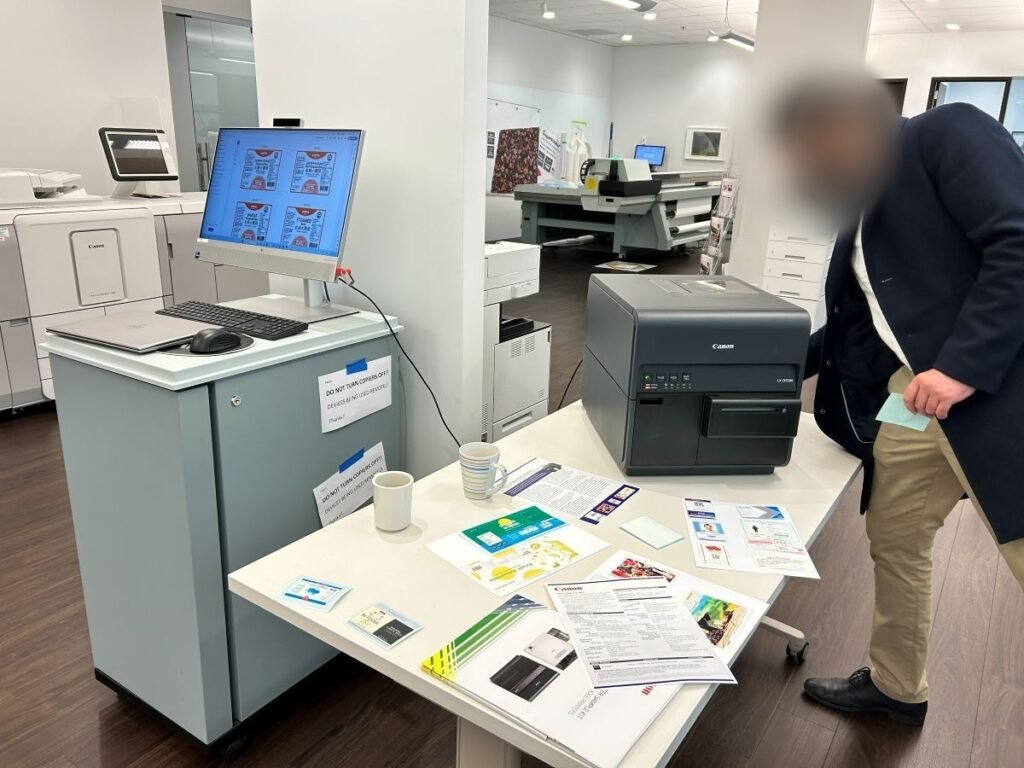 Commercial colour label printer being demonstrated with printed samples at a printing supplier.