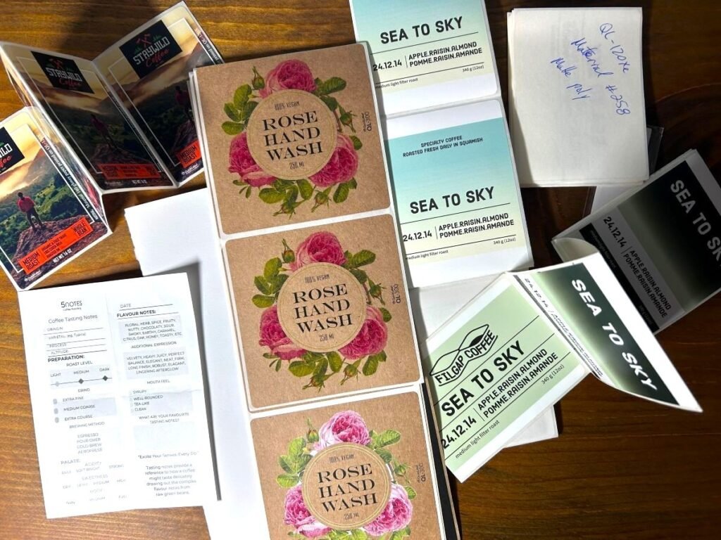 Printed label samples in different colours, shapes and materials arranged on a worktable.
