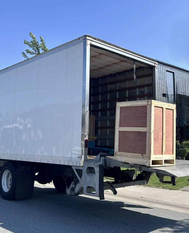 Wooden equipment crate being unloaded from a delivery truck as the Filgap Coffee roasting setup is assembled.