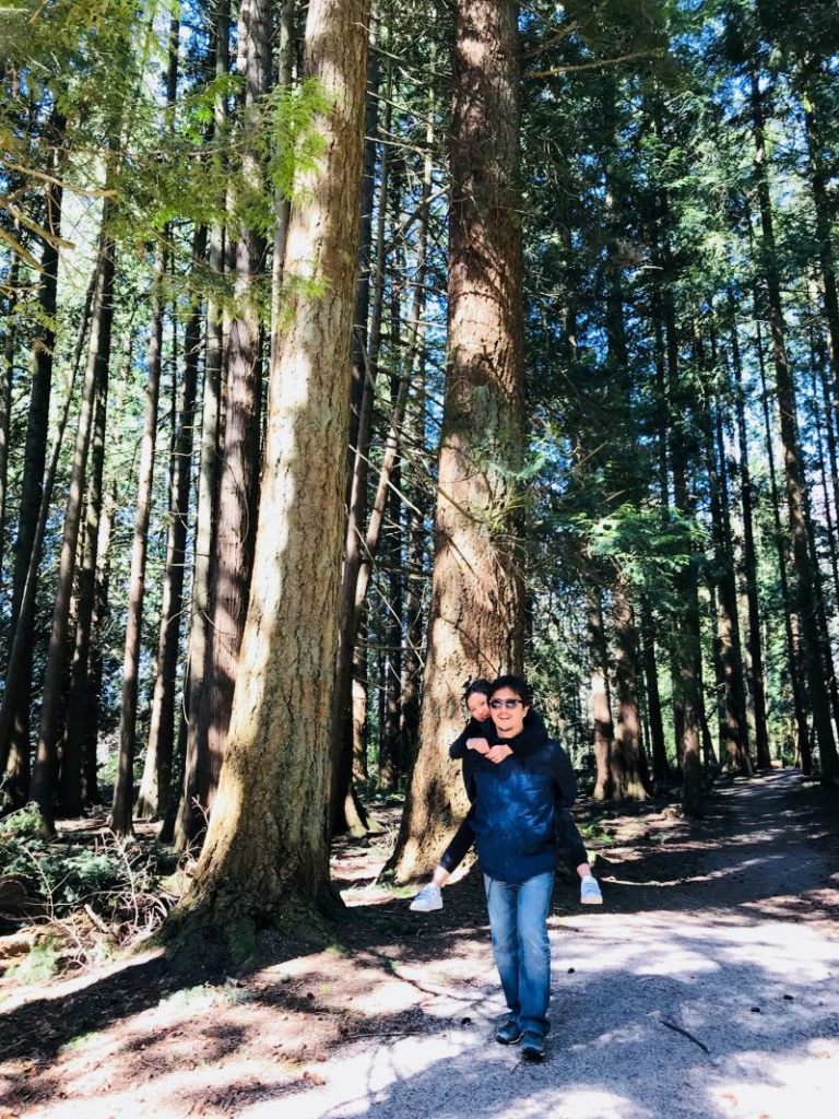 Father carrying his daughter on his back along a forest trail in Squamish in 2018.