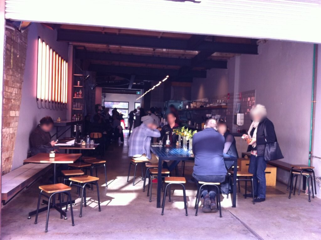 View through the large opening at Reuben Hills showing the long café interior, exposed brick and coffee bar.