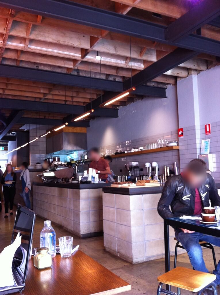 Wide view of customers inside Reuben Hills with the coffee bar, exposed structure and open ceiling visible.