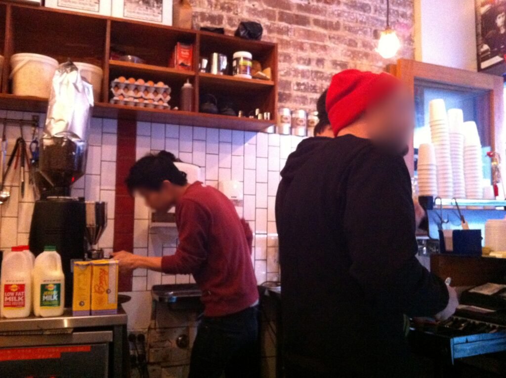 Two staff working beside the grinder and espresso machine in the compact coffee station at Room 10.