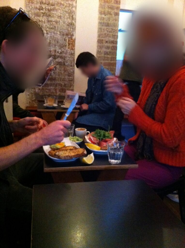 Two customers eating breakfast across a small black table inside Room 10.