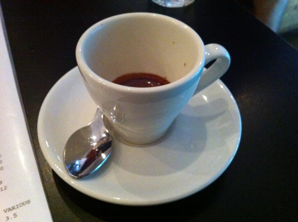 Small white espresso cup containing a short espresso on a white saucer at Room 10.