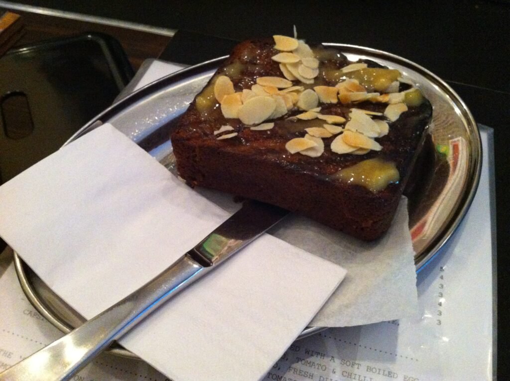 Thick slice of toasted bread topped with sauce and sliced toasted almonds on a metal plate at Room 10.