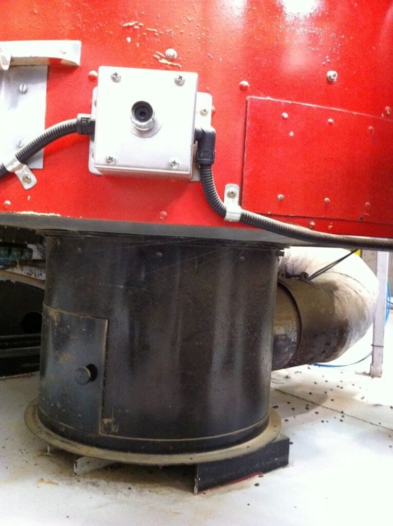Modified underside of a red coffee-roaster cooling tray with a cylindrical metal air outlet