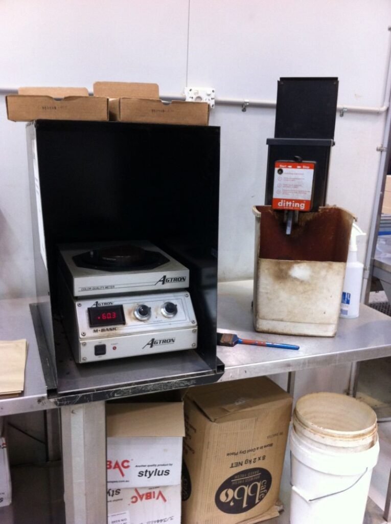 Agtron M-BASIC coffee roast analyzer inside a dark enclosure on a stainless-steel workbench